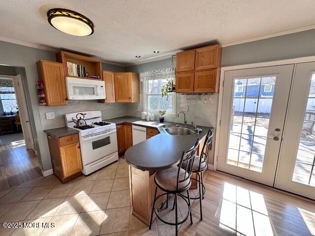 kitchen featuring ornamental molding, white appliances, backsplash, and a sink