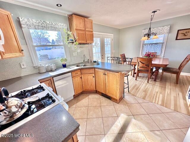 kitchen with dishwasher, backsplash, french doors, a sink, and light tile patterned flooring