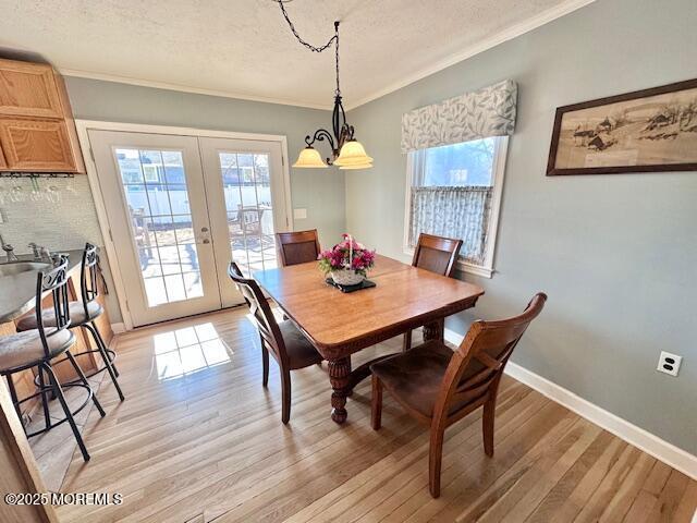 dining room featuring a healthy amount of sunlight, light wood-style flooring, baseboards, and french doors