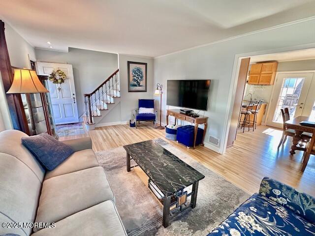 living area with baseboards, stairway, and wood finished floors