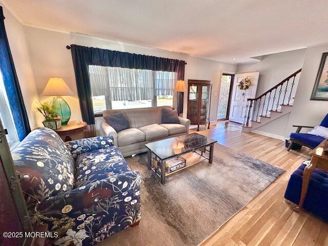 living area with baseboards, stairway, and wood finished floors