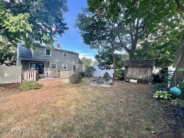 view of yard with an outbuilding, fence, a fire pit, and a storage unit