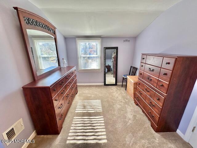 bedroom with lofted ceiling, light colored carpet, visible vents, and baseboards