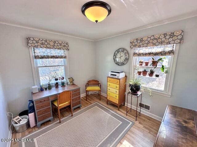 home office featuring a healthy amount of sunlight, visible vents, baseboards, and wood finished floors