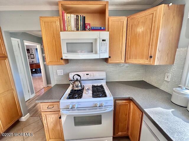 kitchen featuring dark countertops, white appliances, ornamental molding, and backsplash