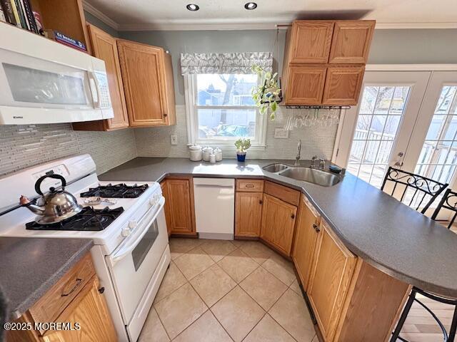 kitchen with ornamental molding, a peninsula, white appliances, and a sink