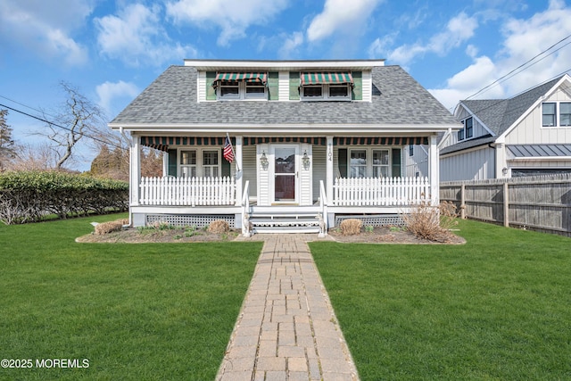 bungalow featuring covered porch, a shingled roof, a front yard, and fence