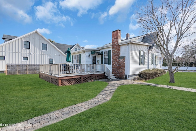 rear view of property with a yard, a shingled roof, a chimney, and a wooden deck