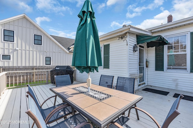 wooden terrace with a grill, fence, and outdoor dining area