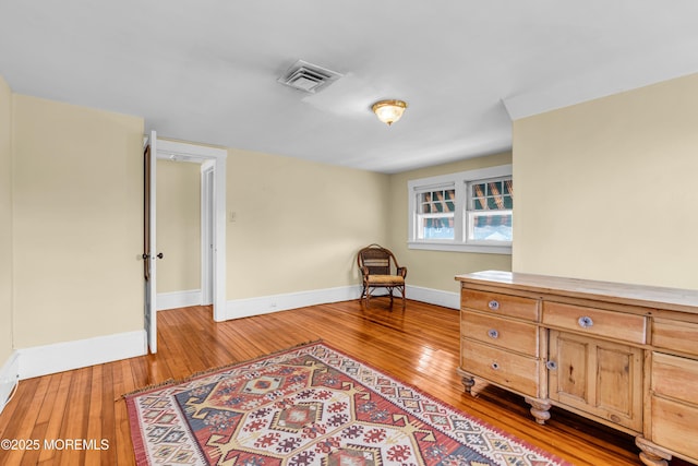 sitting room with light wood-type flooring, visible vents, and baseboards