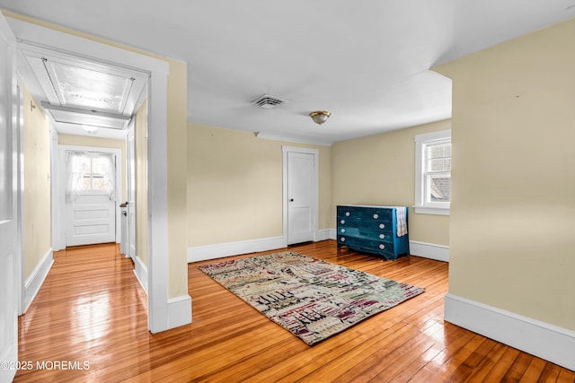 interior space featuring attic access, baseboards, visible vents, and hardwood / wood-style floors