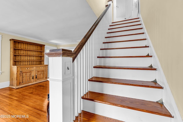 stairs featuring ornamental molding and hardwood / wood-style floors