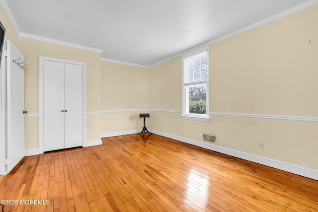 unfurnished bedroom featuring light wood-type flooring, visible vents, baseboards, and crown molding