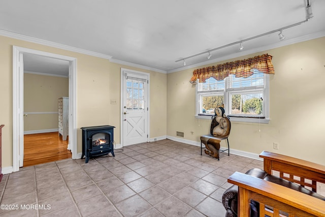 foyer entrance with a wood stove, light tile patterned floors, baseboards, and ornamental molding