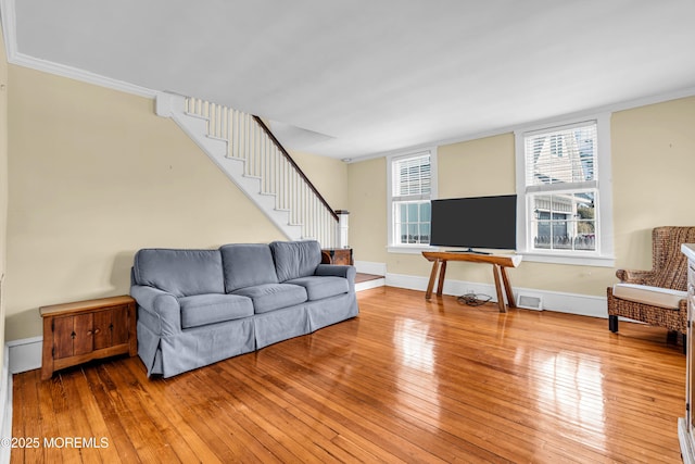 living area with visible vents, light wood-style flooring, ornamental molding, baseboards, and stairs