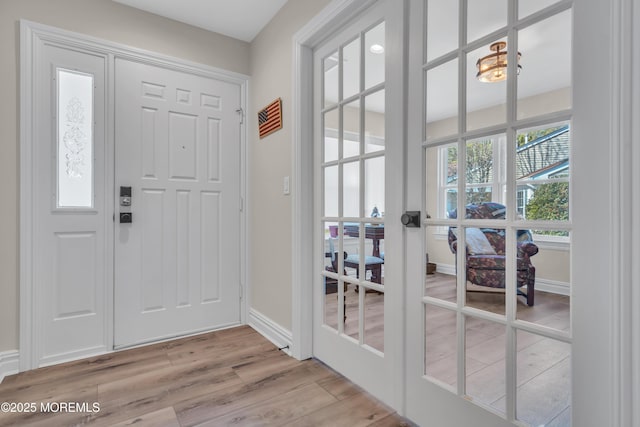 entryway with light wood-style floors, french doors, and baseboards