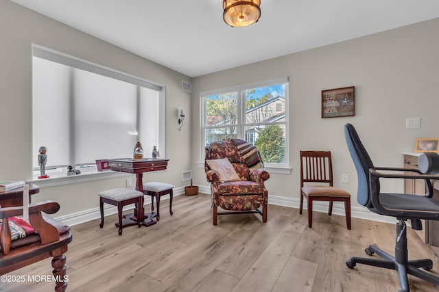 office space with light wood finished floors, visible vents, and baseboards