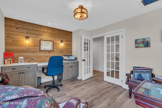 home office featuring french doors, visible vents, wood walls, and light wood-style flooring