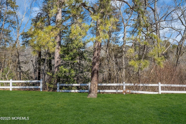 view of yard with fence and a forest view