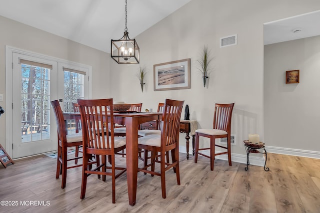 dining area with wood finished floors, visible vents, baseboards, vaulted ceiling, and french doors