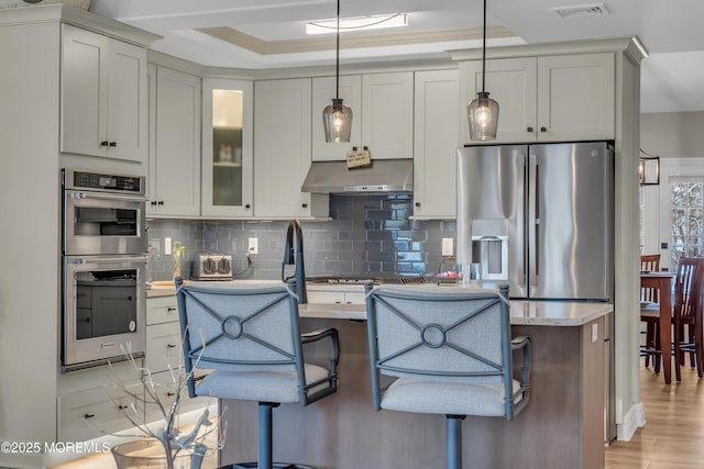 kitchen with appliances with stainless steel finishes, tasteful backsplash, visible vents, and extractor fan