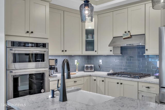 kitchen with a sink, stainless steel appliances, backsplash, and under cabinet range hood