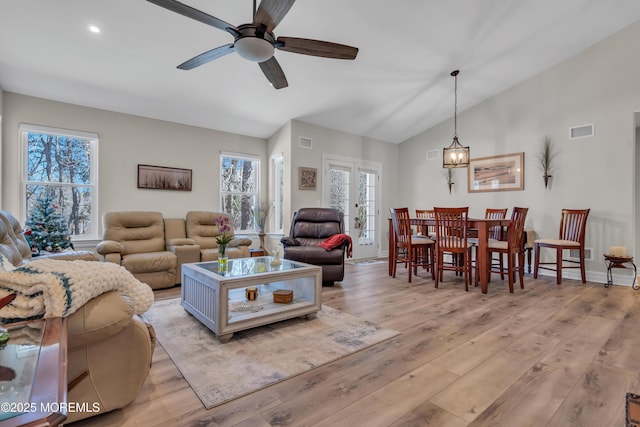 living room featuring light wood-style flooring, visible vents, and vaulted ceiling