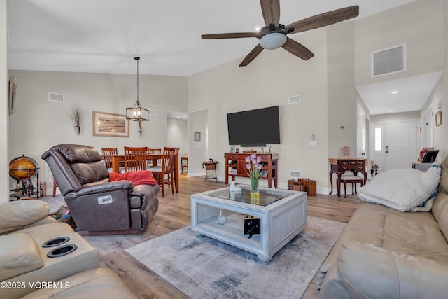 living room with ceiling fan, light wood-type flooring, visible vents, and baseboards