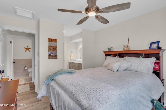 bedroom with a ceiling fan, light wood-type flooring, visible vents, and ensuite bathroom