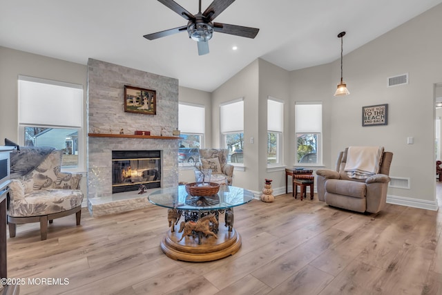 living area with vaulted ceiling, a fireplace, and visible vents