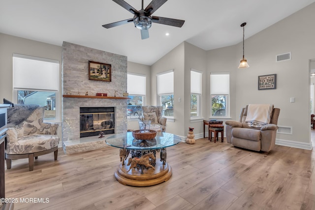 living room featuring lofted ceiling, visible vents, and a stone fireplace