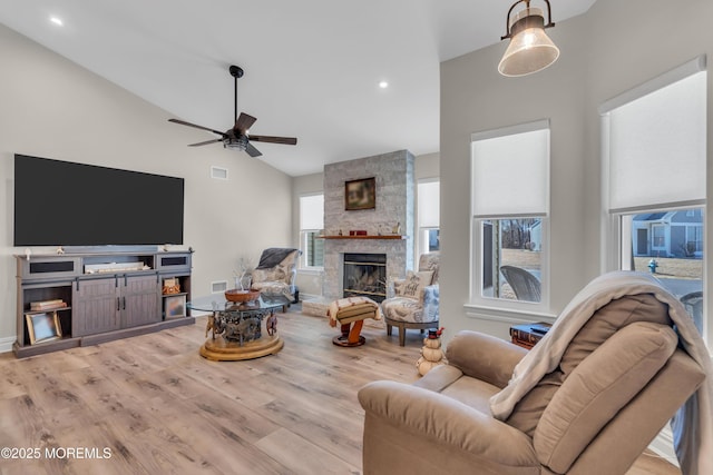 living room featuring ceiling fan, a fireplace, visible vents, and wood finished floors