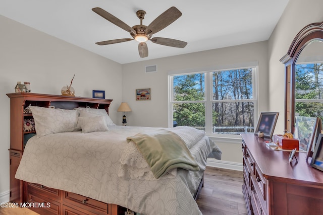 bedroom with dark wood-style floors, visible vents, ceiling fan, and baseboards