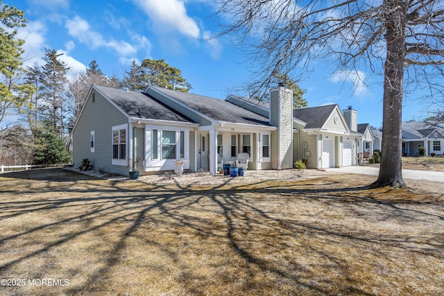 view of front of home featuring driveway, a chimney, an attached garage, and a residential view