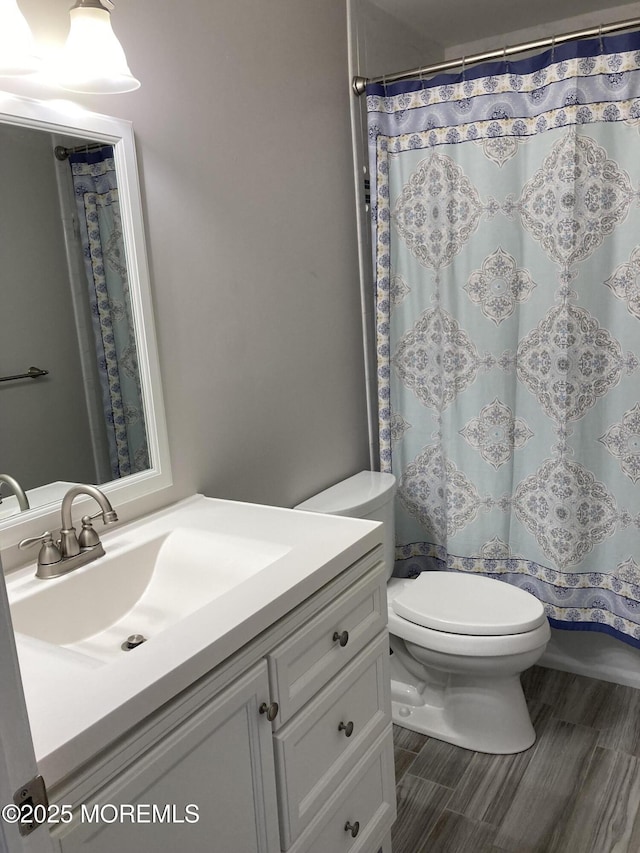 full bathroom featuring a shower with shower curtain, vanity, and toilet