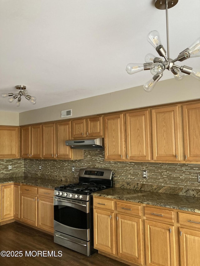 kitchen with under cabinet range hood, stainless steel gas range oven, visible vents, and backsplash