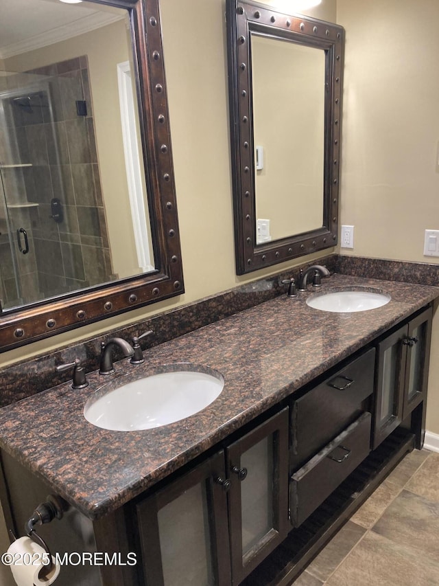 bathroom with crown molding, a stall shower, a sink, and double vanity