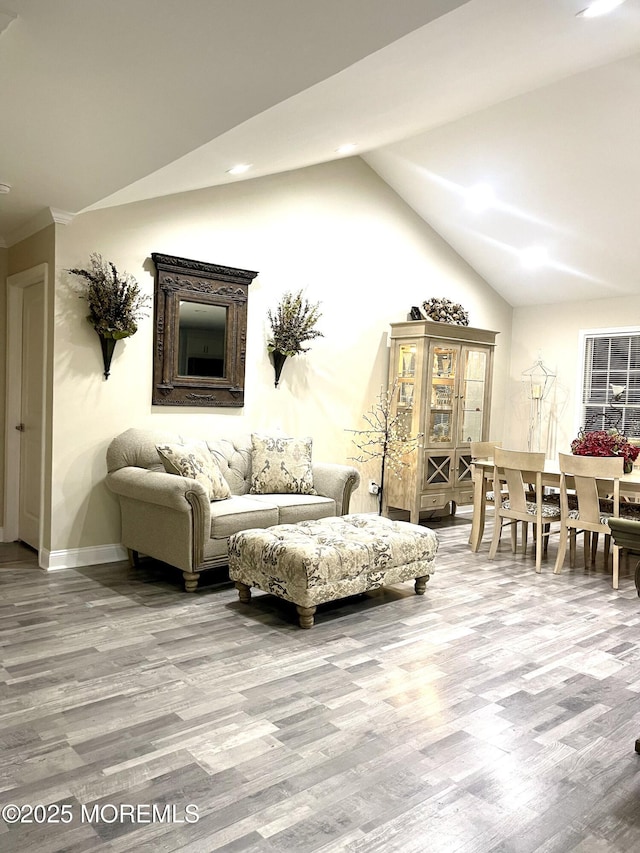 living area featuring baseboards, lofted ceiling, and wood finished floors