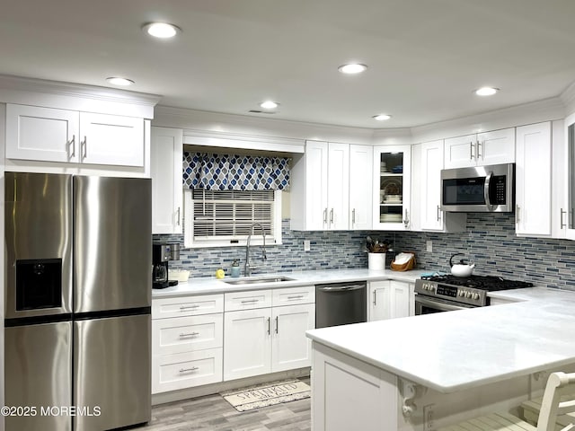 kitchen featuring appliances with stainless steel finishes, white cabinetry, light countertops, and a sink