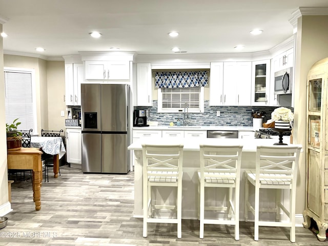 kitchen with a breakfast bar, a sink, tasteful backsplash, appliances with stainless steel finishes, and light countertops