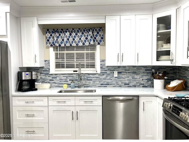 kitchen with white cabinetry, stainless steel appliances, light countertops, and a sink