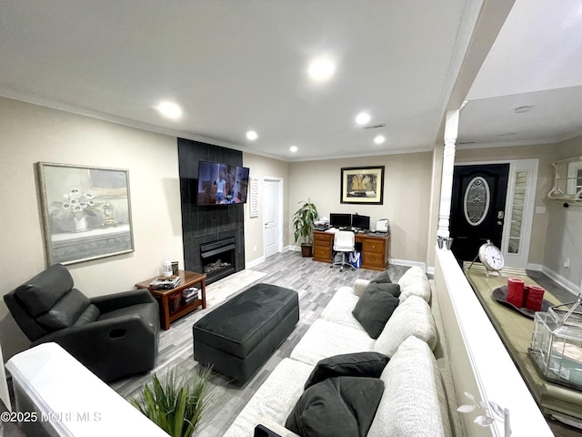 living area featuring light wood finished floors, crown molding, decorative columns, recessed lighting, and a fireplace