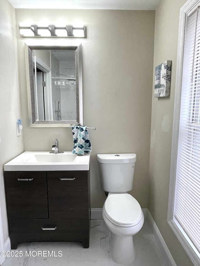 bathroom with an enclosed shower, toilet, marble finish floor, baseboards, and vanity