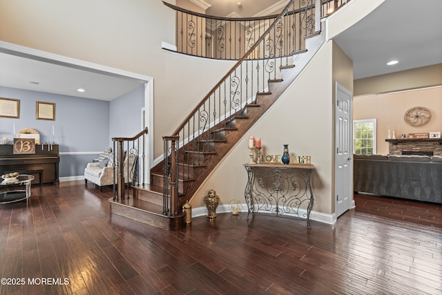 staircase with recessed lighting, a high ceiling, a fireplace, wood finished floors, and baseboards