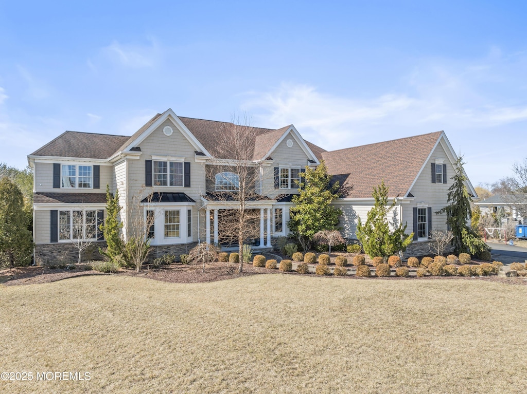 traditional home featuring stone siding and a front yard