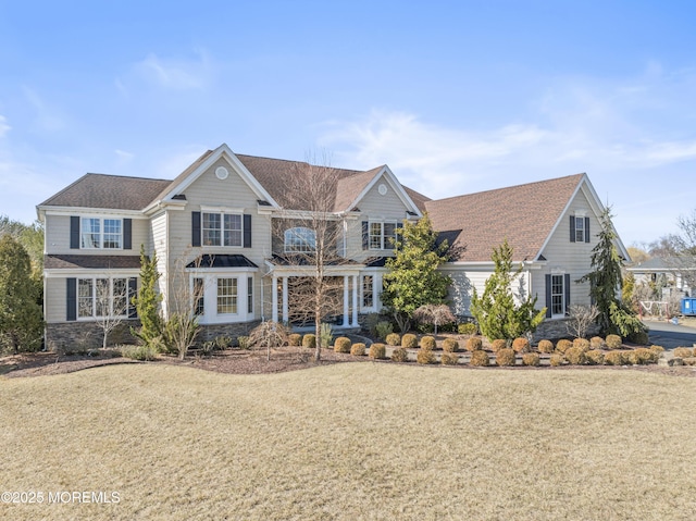 traditional home featuring stone siding and a front yard