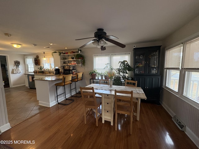 dining room featuring a wealth of natural light, dark wood-style flooring, visible vents, and ceiling fan