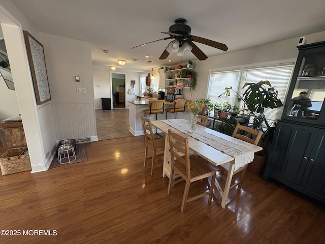 dining area with a wainscoted wall, ceiling fan, and wood finished floors