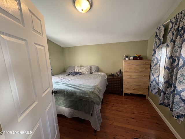 bedroom with lofted ceiling, wood finished floors, and baseboards