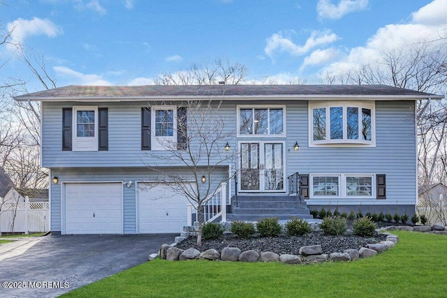 bi-level home with a garage, driveway, and a front lawn